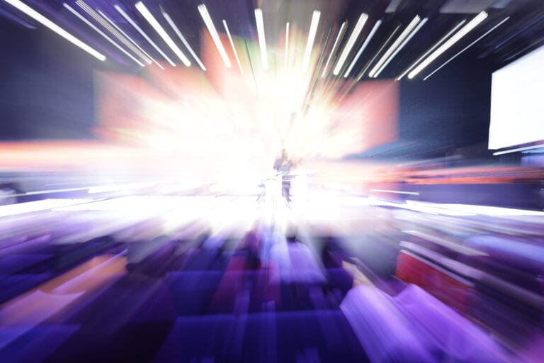 Abstract photograph with radiant beams of white, blue, and purple light exploding outward from a central point, creating a dramatic starburst effect